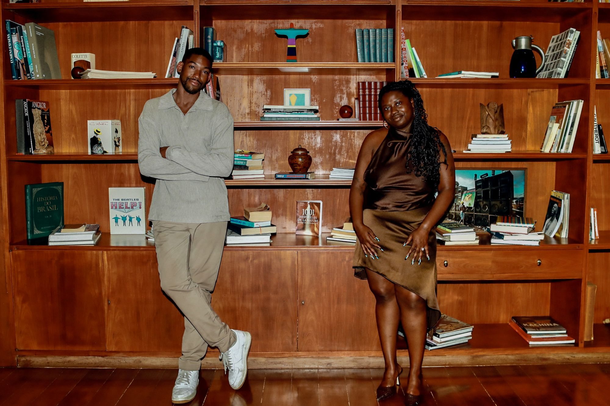Joshua German and Janel Moore in front of a wall of bookshelves